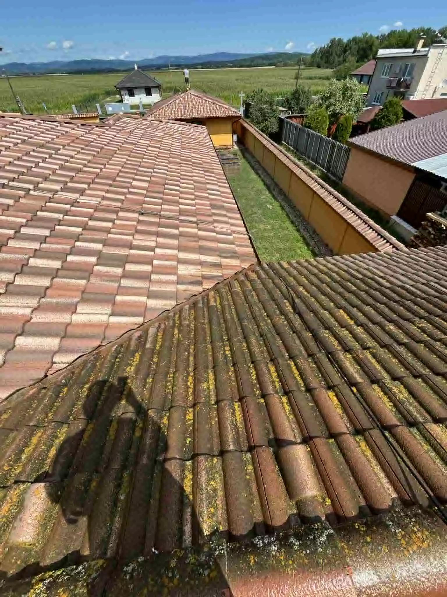Strecha pred impregnáciou so žltými lišajníkmi a machom – kontrast s čistou škridlou v pozadí